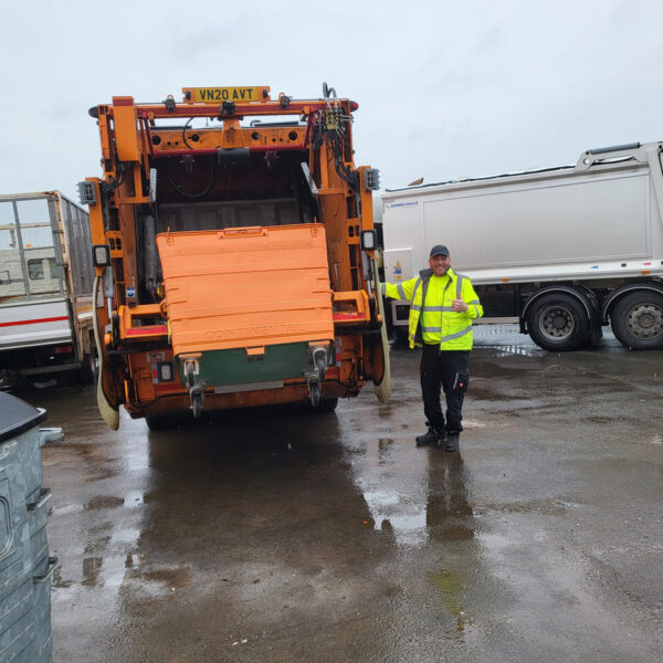 Commercial Waste wagon in action with a bin operative parked between a domestic wagon on the right and a waste cage on the left