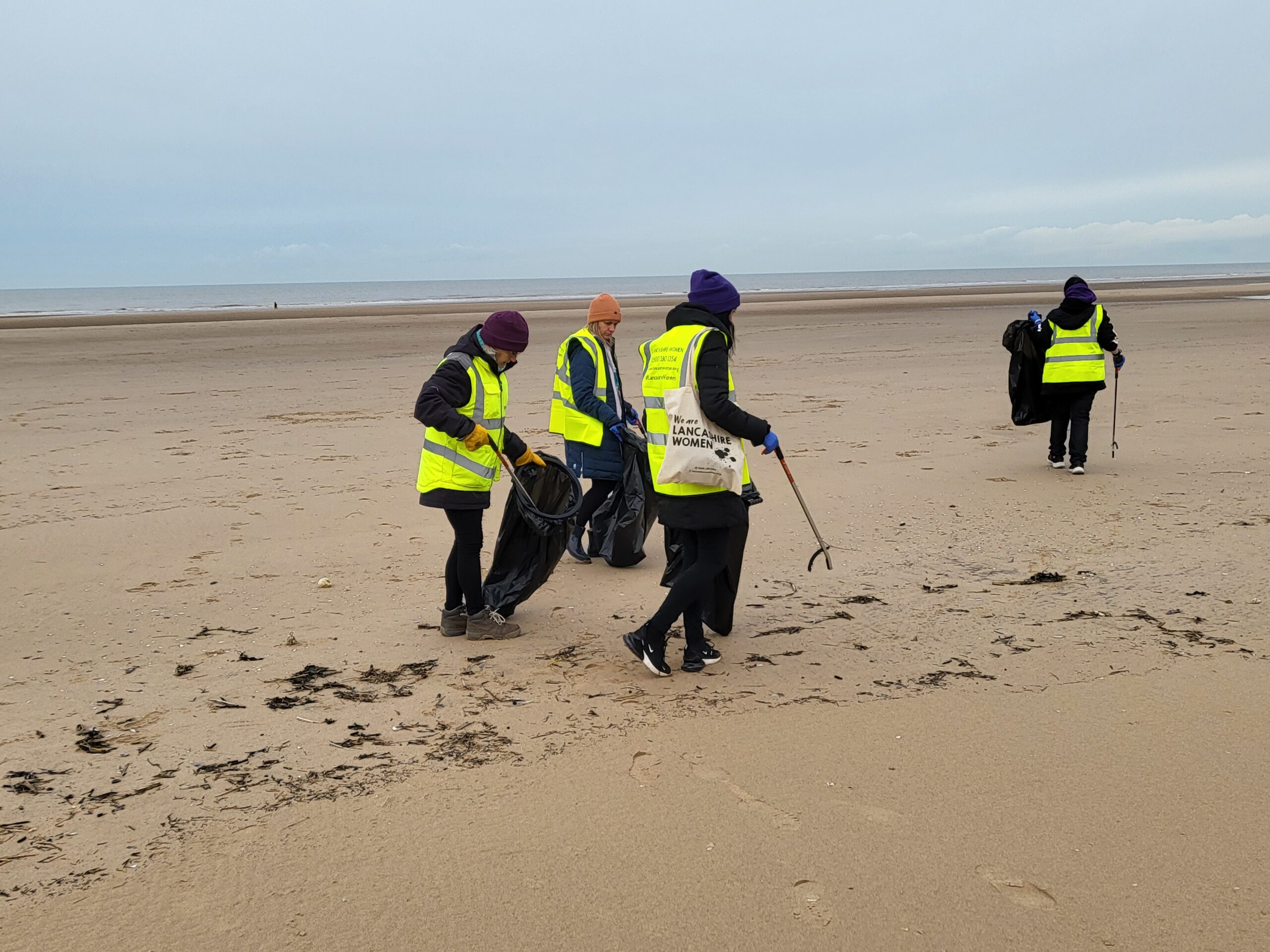 Enveco host litter picking events with Lancashire Women, image of 4 women on Blackpool Beach litter picking.