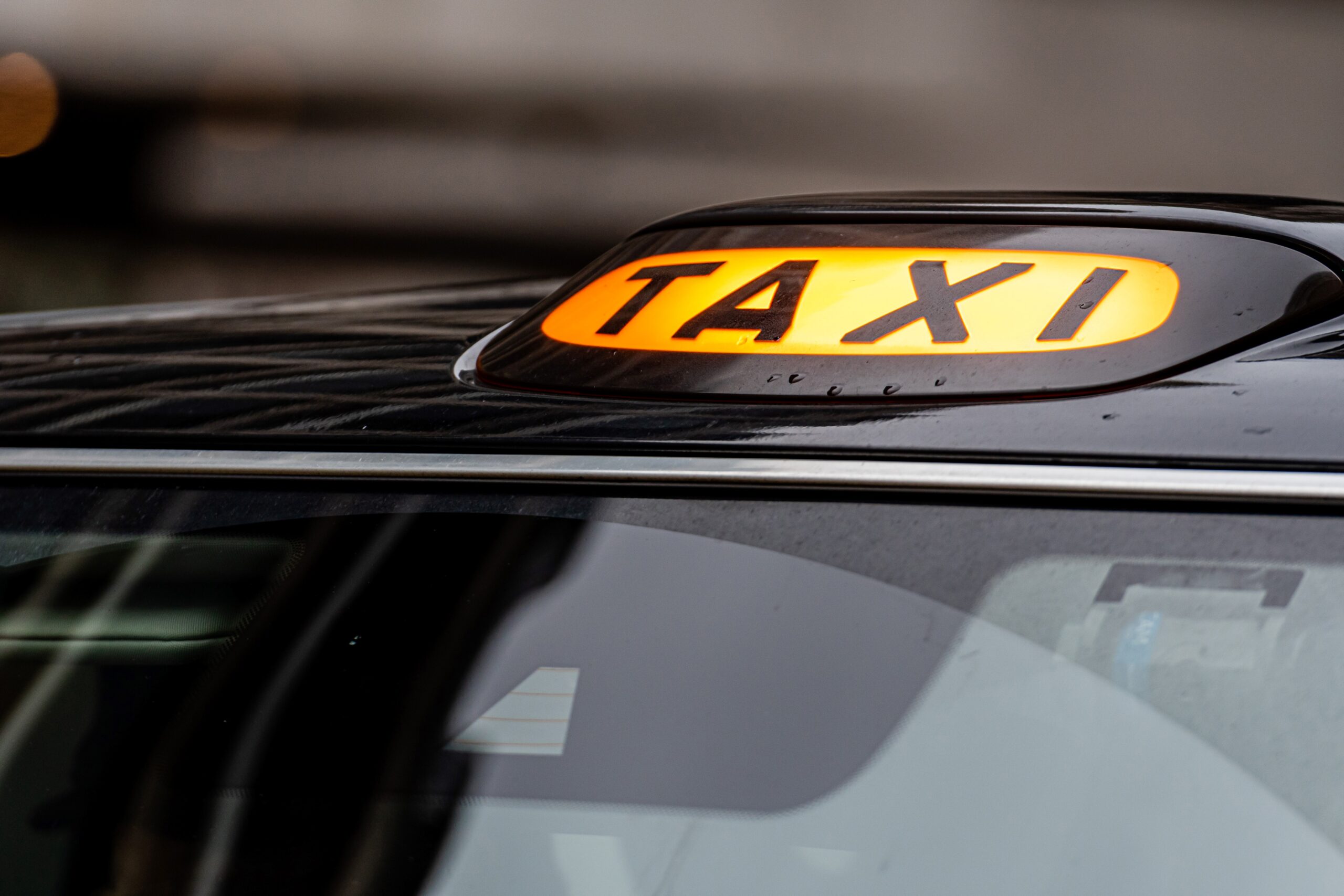 A british london black taxi cab sign with defocused background