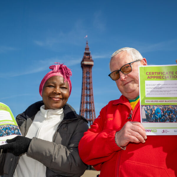 Two litter pick volunteers holding a litter pick certificate on Blackpool's sea front - with the tower behind them